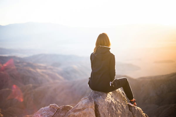 A woman in exercise gear watching the sun rise on a mountain