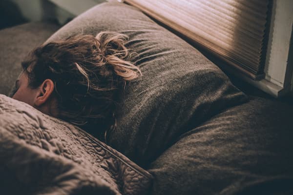 A young woman sleeping under the covers in a bed