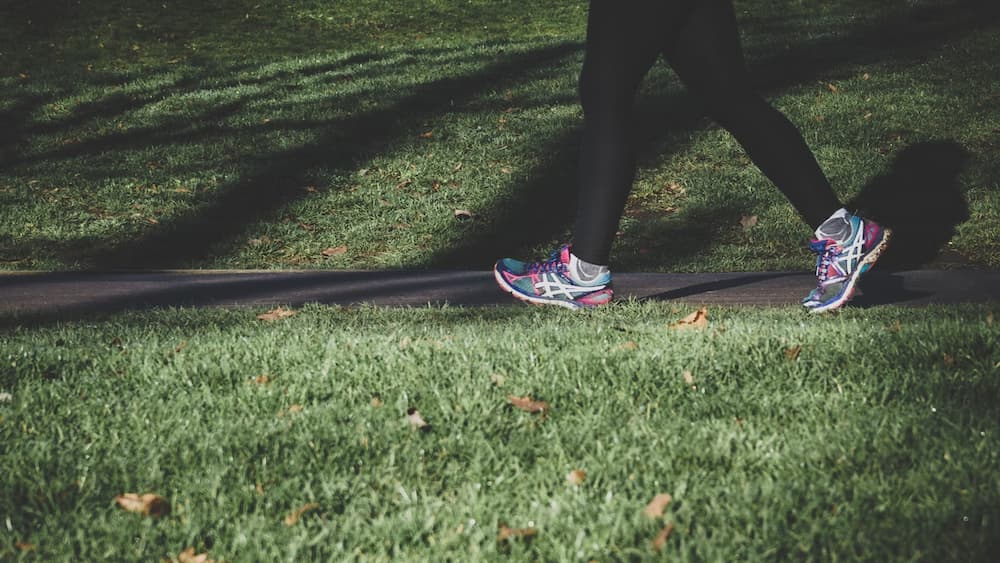 a woman running on a trail, with only her legs and shoes visible.